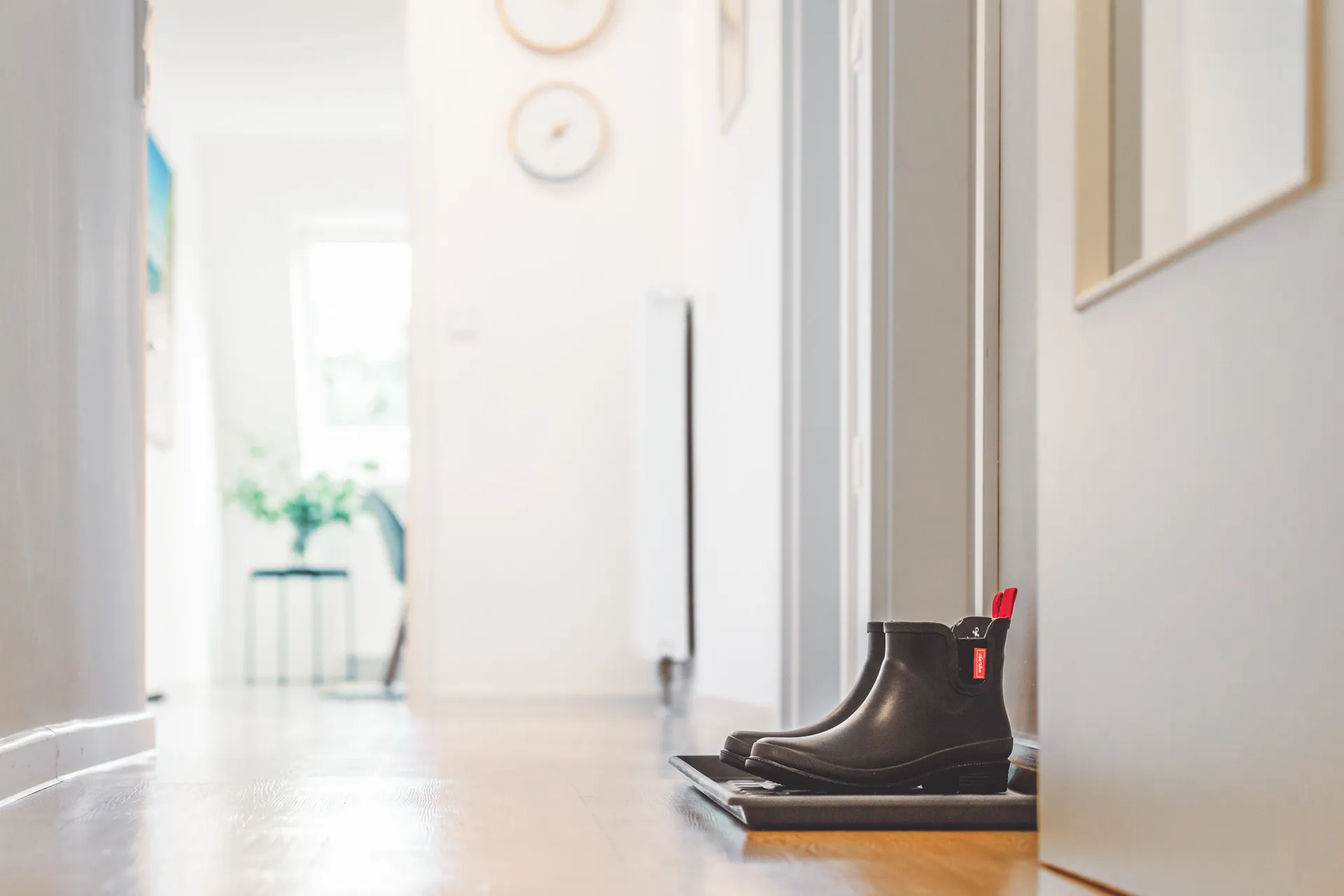 Blick durch den Flur der Wohnung, im Vordergrund ein Paar schwarze Gummistiefel auf einer Schuhmatte