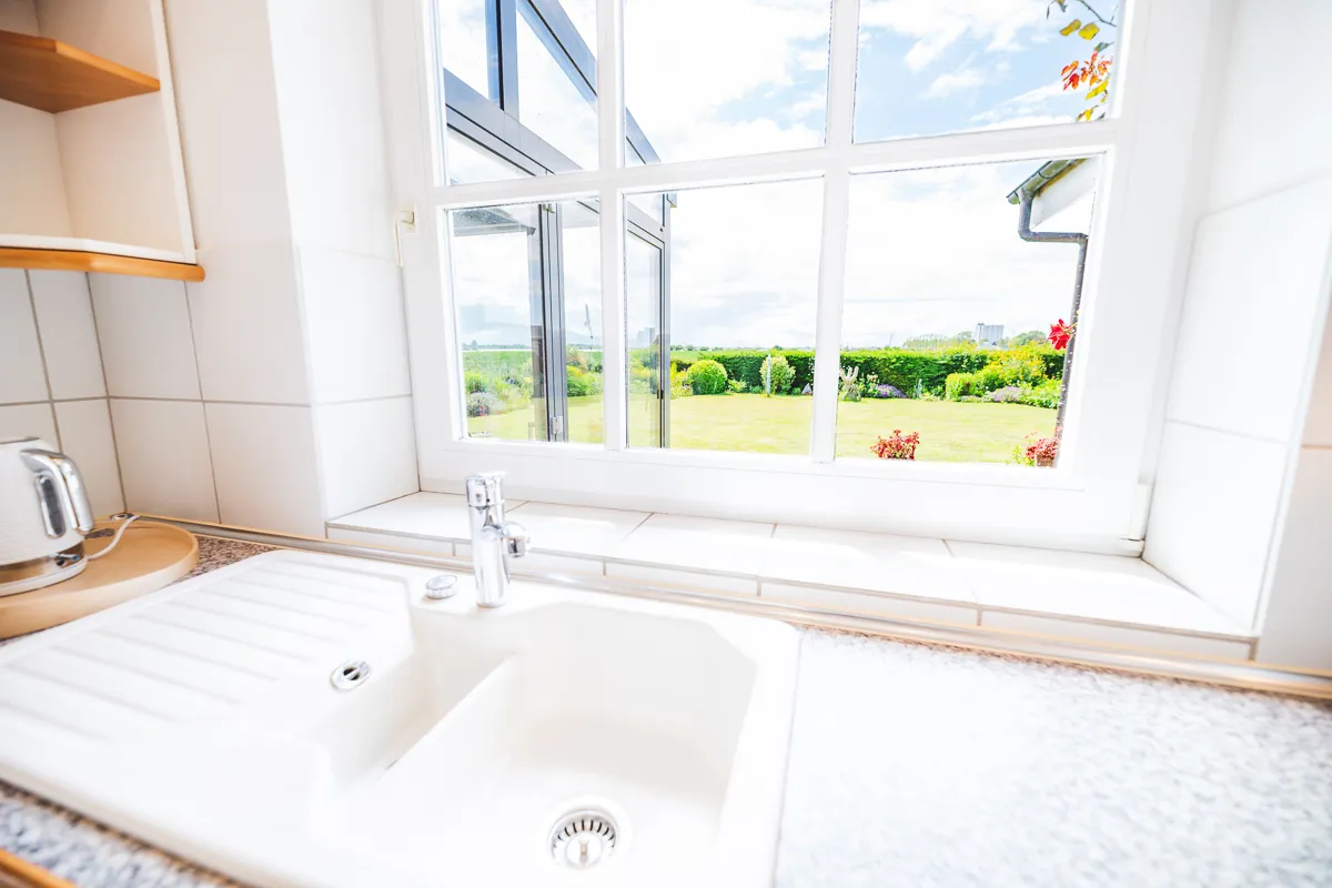 Küchenspüle unter dem Fenster mit Blick auf den Garten und den angrenzenden Wintergarten